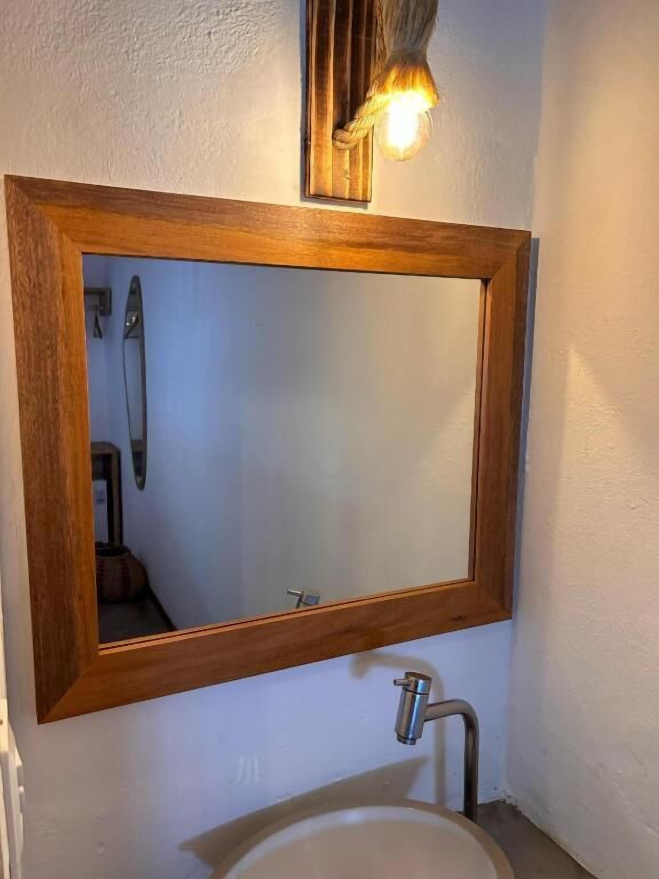 Un baño con un espejo de marco de madera, un lavamanos y un perchero para toallas.