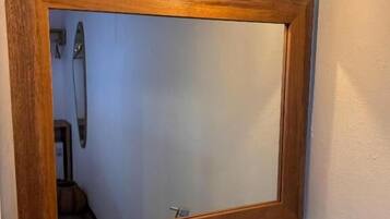 Un baño con un espejo de marco de madera, un lavamanos y un perchero para toallas.
