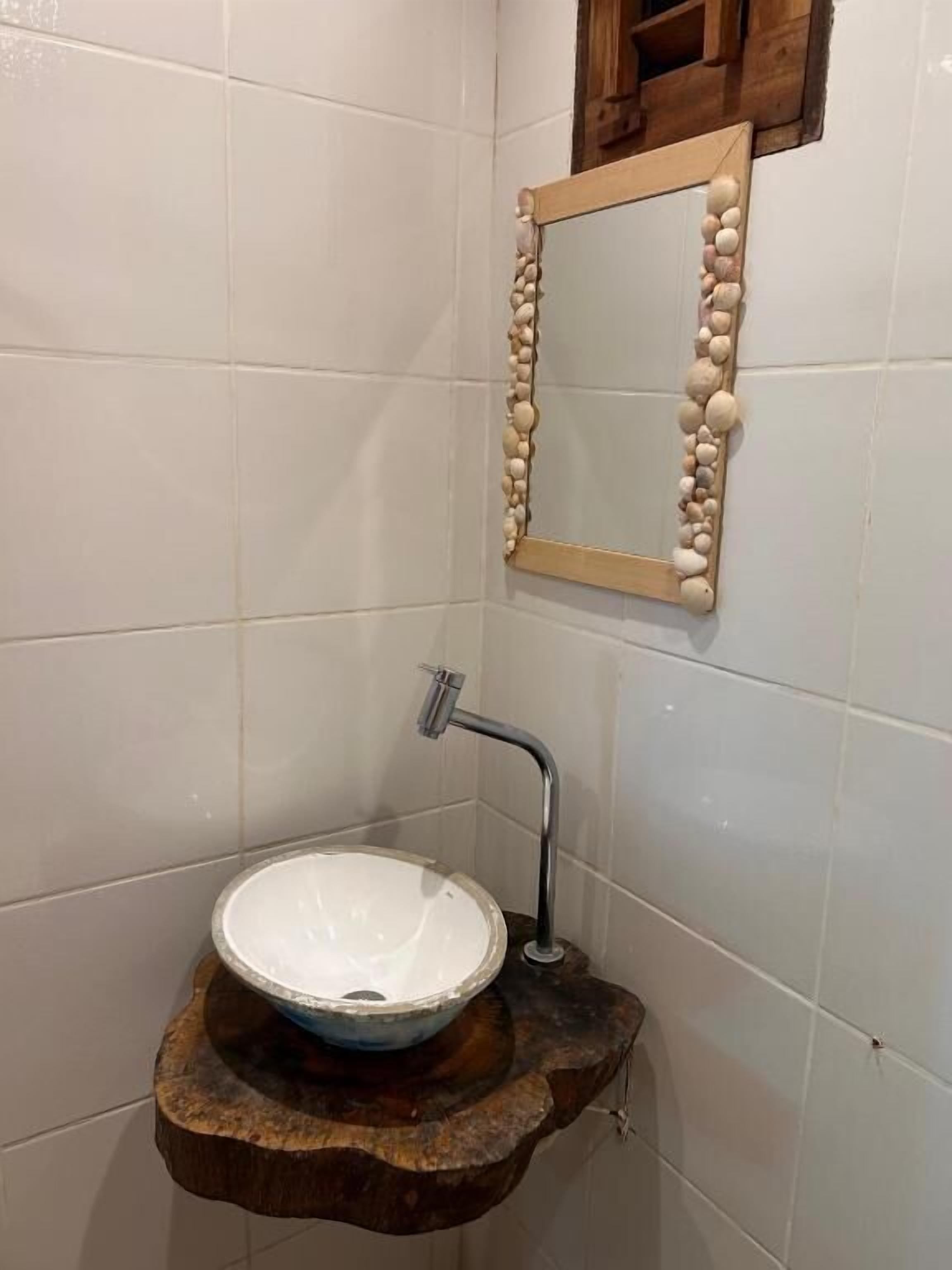 A bathroom with a wooden sink, a mirror with a stone frame, and a shower.
