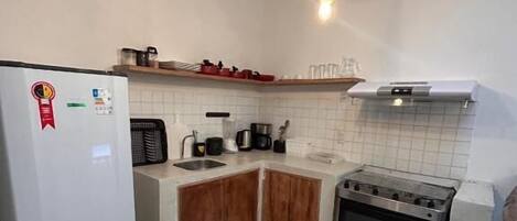Una cocina equipada con refrigerador, estufa, microondas y gabinetes de madera.