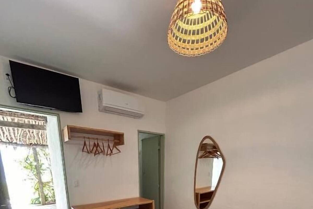Un dormitorio con cama, un armario de madera, un espejo y una lámpara colgante.