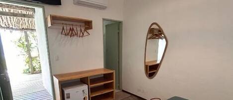 A bedroom with a bed, a wooden cabinet, a mirror, and a hanging light fixture.
