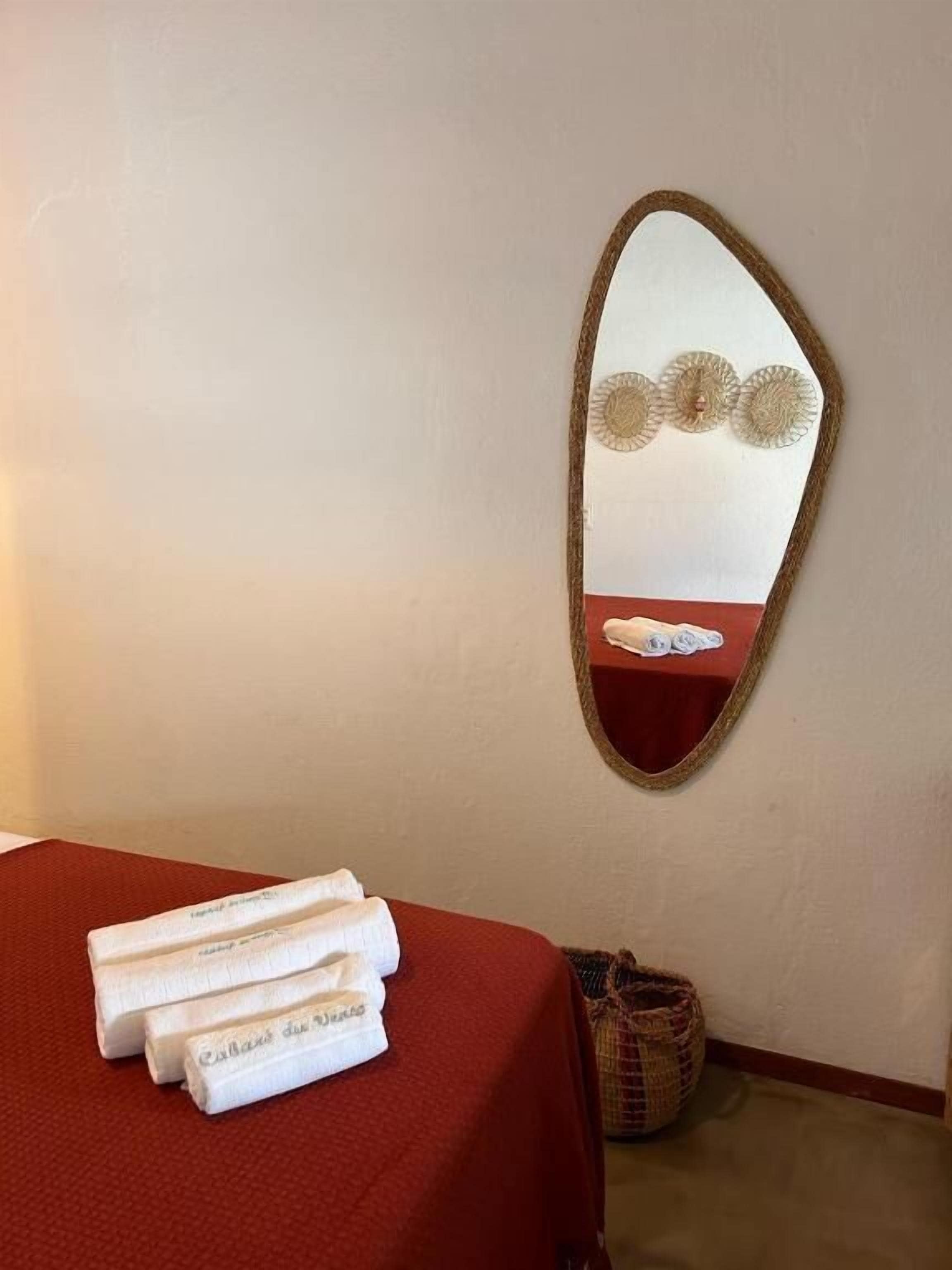 Habitación de hotel con cama, espejo y una mesita con toallas.
