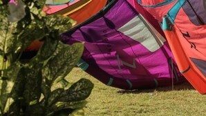Colorful kites and flags on a beach with the ocean in the background. - Cabaré du Vento (Cruz)