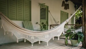 A hammock on a porch with green shutters, a chair, and potted plants. - Cabaré du Vento (Cruz)