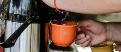 Una persona sirve café desde una cafetera de acero inoxidable en una taza.