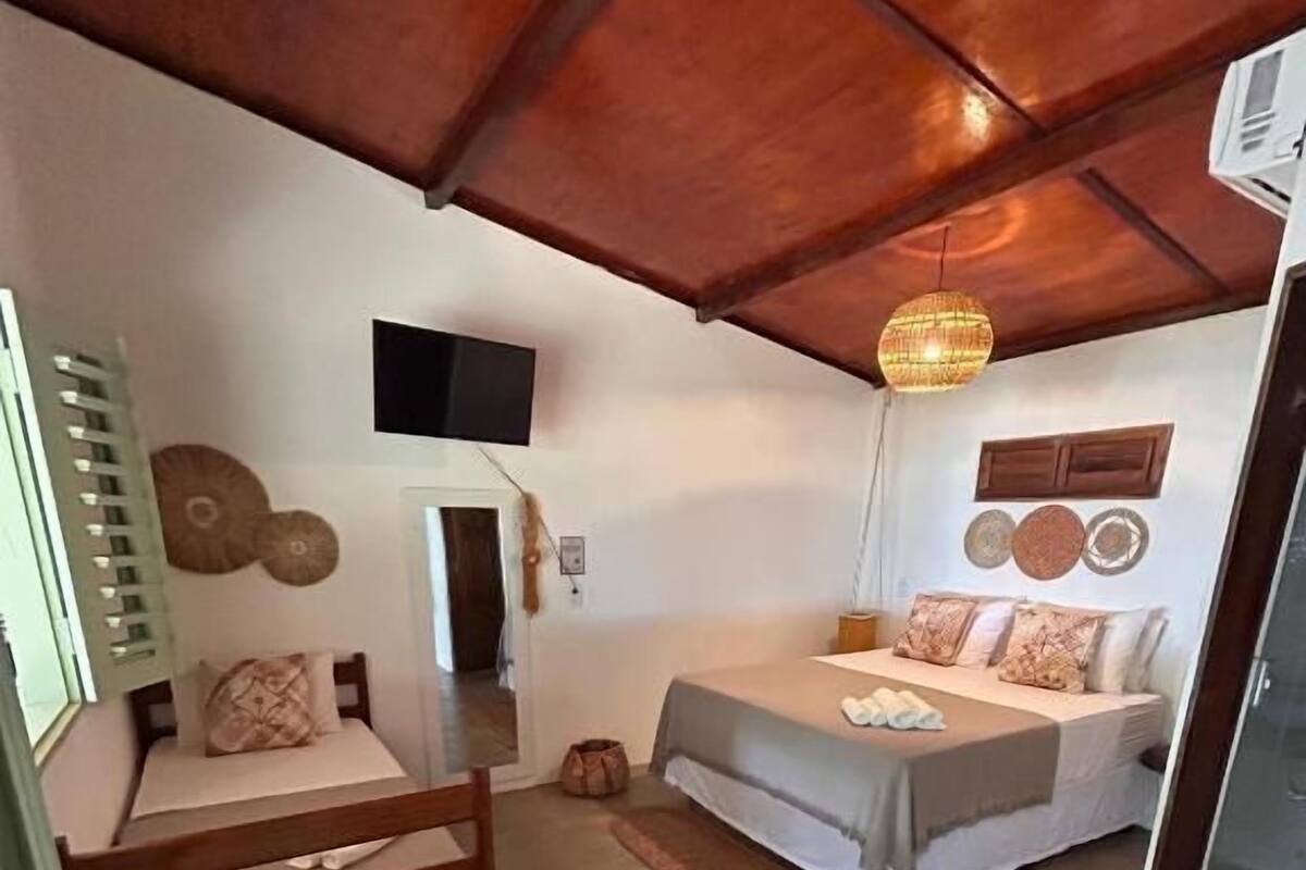 Una habitación pequeña y funcional con cama, escritorio y televisión.