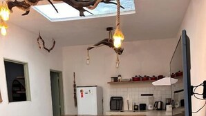 A kitchen with a central island, stools, a refrigerator, and a microwave. - Cabaré du Vento (Cruz)