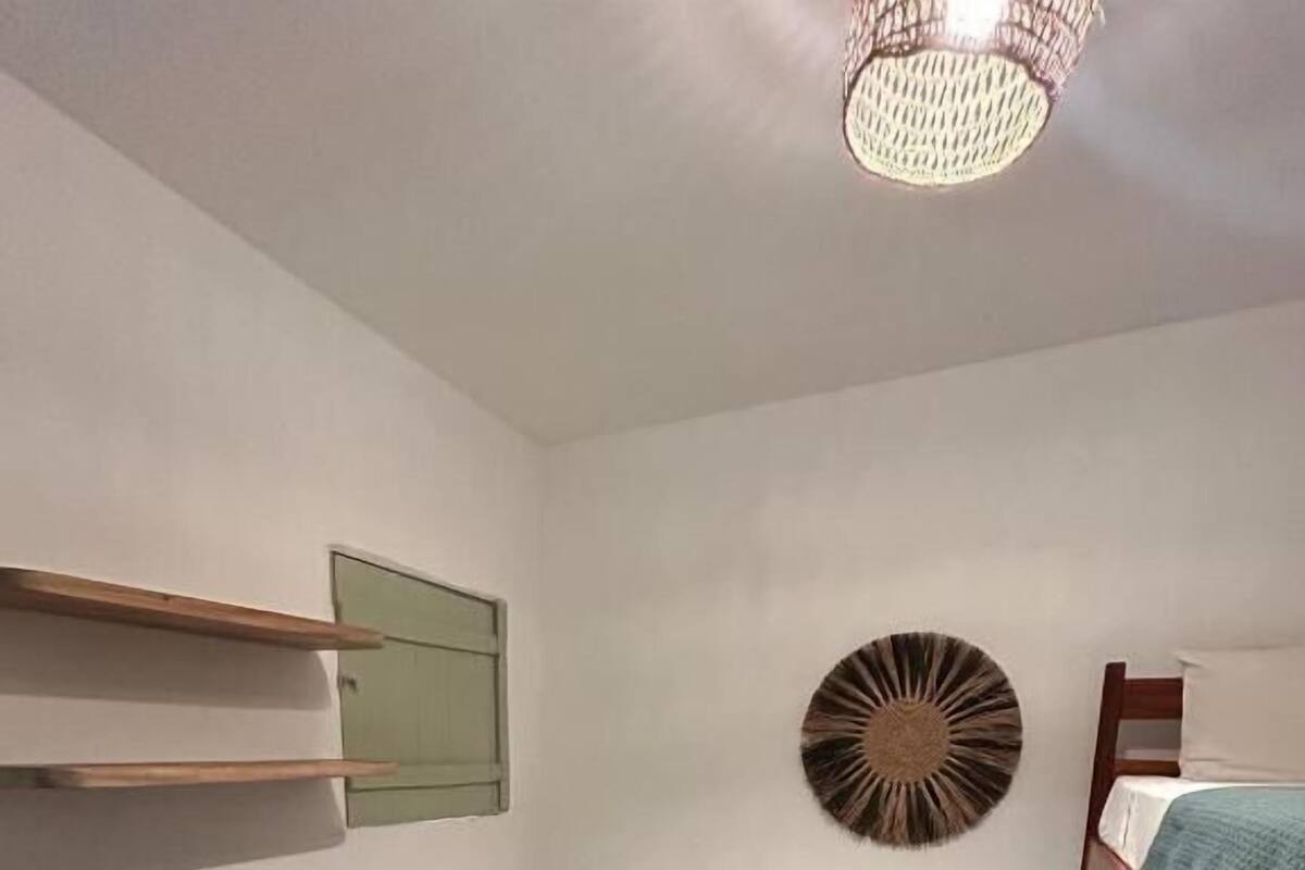 Una habitación con una cama litera, una cama individual, una mesita pequeña, un espejo montado en la pared y un adorno decorativo.