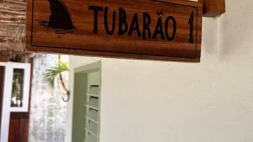 Un letrero de madera con la silueta de un tiburón y el nombre 'TUBARÃO 1' montado en una pared.