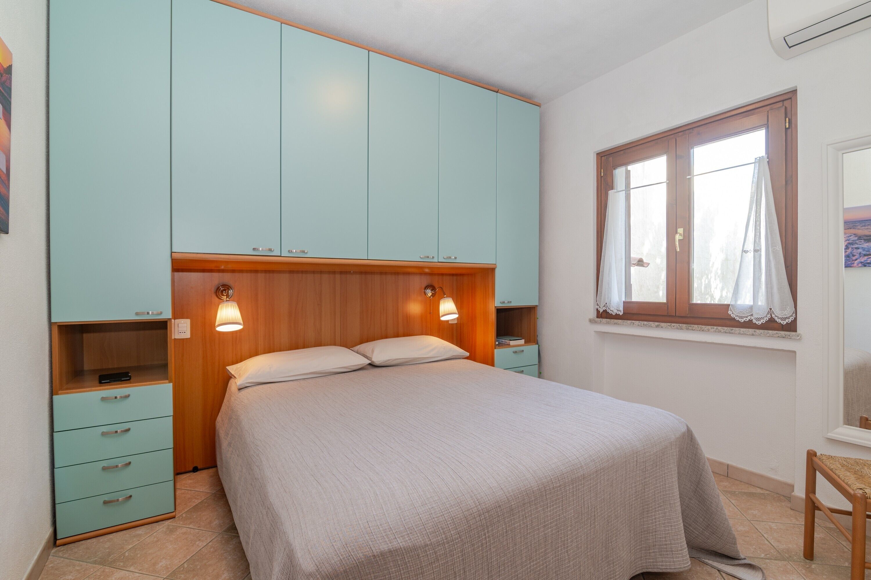 Une chambre à coucher avec un lit, une armoire, une table de chevet et une fenêtre avec des rideaux.
