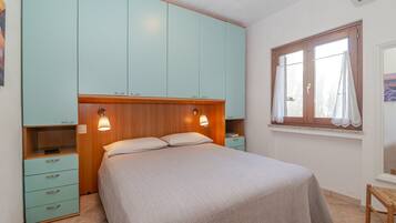 Une chambre à coucher avec un lit, une armoire, une table de chevet et une fenêtre avec des rideaux.