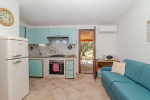 Una cocina compacta con gabinetes azul turquesa, un refrigerador blanco y una estufa.