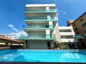 Ein mehrstöckiges Gebäude mit Balkonen, einem Schwimmbad und blauem Himmel.