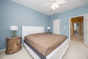 A bedroom with a bed, two nightstands, a ceiling fan, and a door leading to another room. - Sunset Island - 5 Brs/ Sleeps 12 / 2 pools (Ocean City)