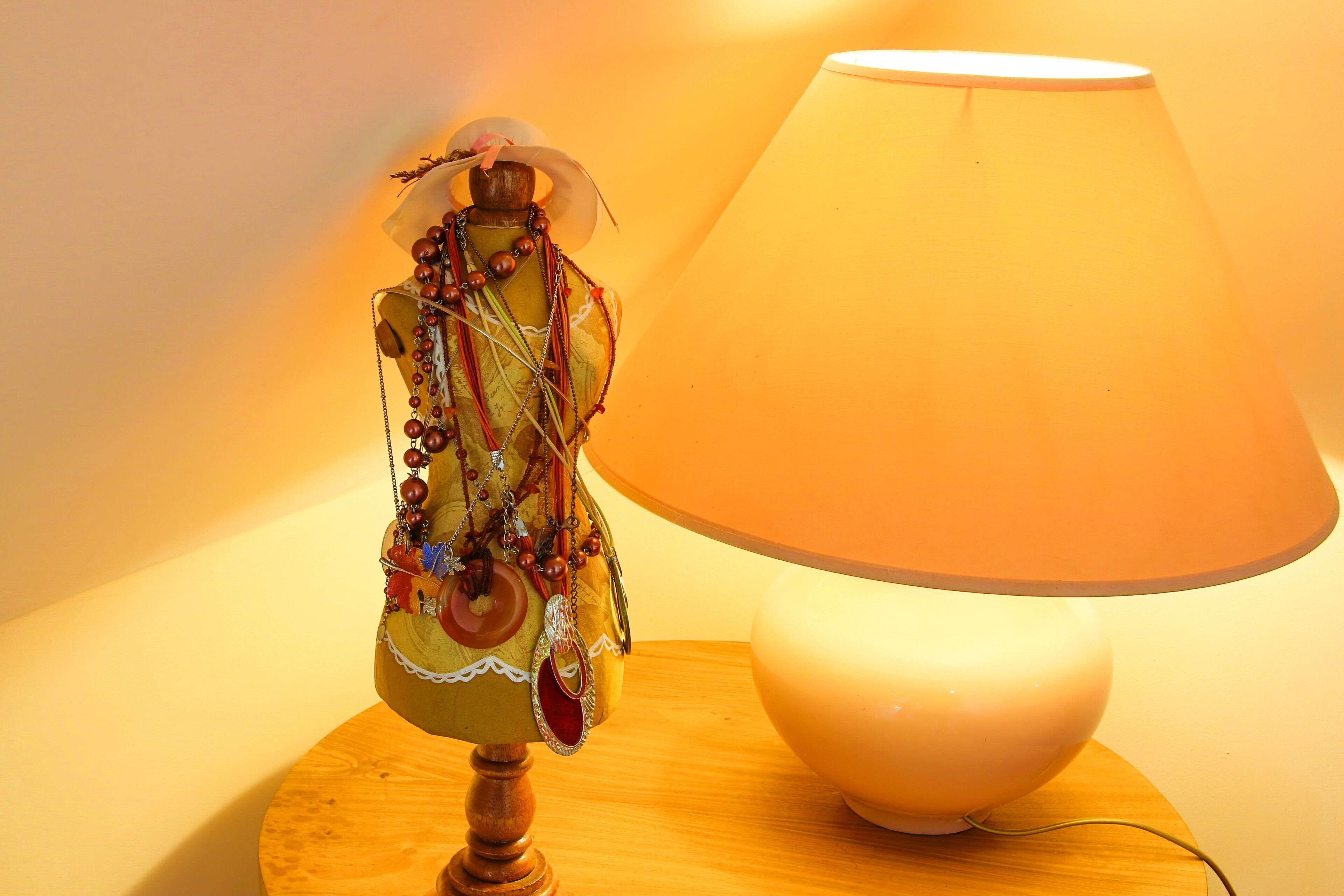 Un manichino con accessori su un tavolo di legno vicino a una lampada.