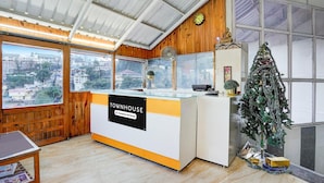 A cozy room with a wooden interior, a glass counter labeled "TOWNHOUSE," a small Christmas tree, and a view of the city through large windows. - Townhouse Mall Road Near Library Chowk (Dehradun)