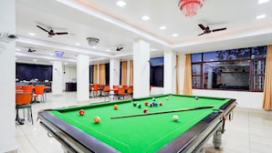 A pool table in a well-lit room with ceiling fans and a chandelier. - Townhouse Mall Road Near Library Chowk (Dehradun)