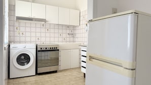 Een functionele keuken met een wasmachine, oven en een witte koelkast.