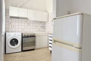A compact kitchen with a washing machine, oven, and a white refrigerator. - SE233 - Senigallia, two-bedroom apartment just steps from the sea (Senigallia)