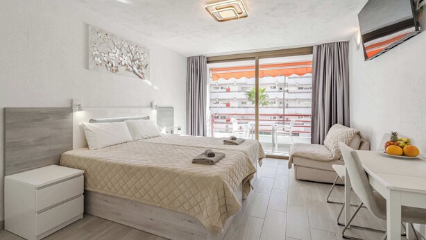 Ein Hotelzimmer mit Bett, Schreibtisch, Stuhl, Fernseher und einem Balkon mit Blick.