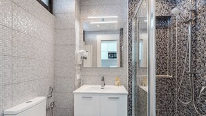 Ein modernes Badezimmer mit Toilette, Waschbecken, Spiegel und Duschbereich.