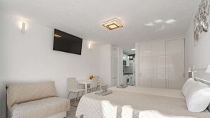 Ein modernes Schlafzimmer mit Bett, Sofa, Schreibtisch und Kleiderschrank.