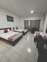 Habitación de hotel con tres camas, un escritorio y una silla.