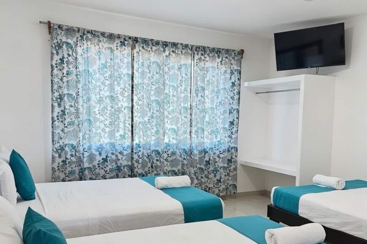 A hotel room with two beds, a TV, and a window with curtains.