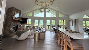 A spacious kitchen with a large chandelier, a stone fireplace, and a dining area with wooden bar stools. - Newly renovated 4B, 4BA in Deerfield (LaFollette)