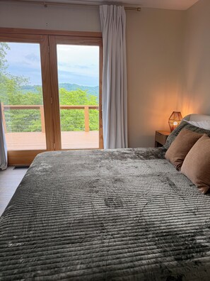 A bedroom with a large bed, a nightstand with a lamp, and a view of greenery through a sliding door. - Newly renovated 4B, 4BA in Deerfield - Interior pics will be posted soon! (LaFollette)