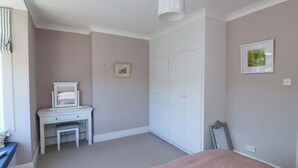 Een slaapkamer met een bed, een bureau, een kast en een hanglamp.