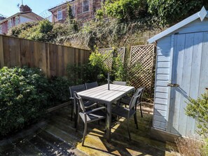 A wooden table with chairs in a garden area with a wooden fence and a shed in the background. - 43 Sandquay Road (Dartmouth)