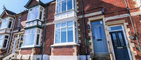 A row of terraced houses with a central entrance, a small front garden, and a visible number '43' on the door.