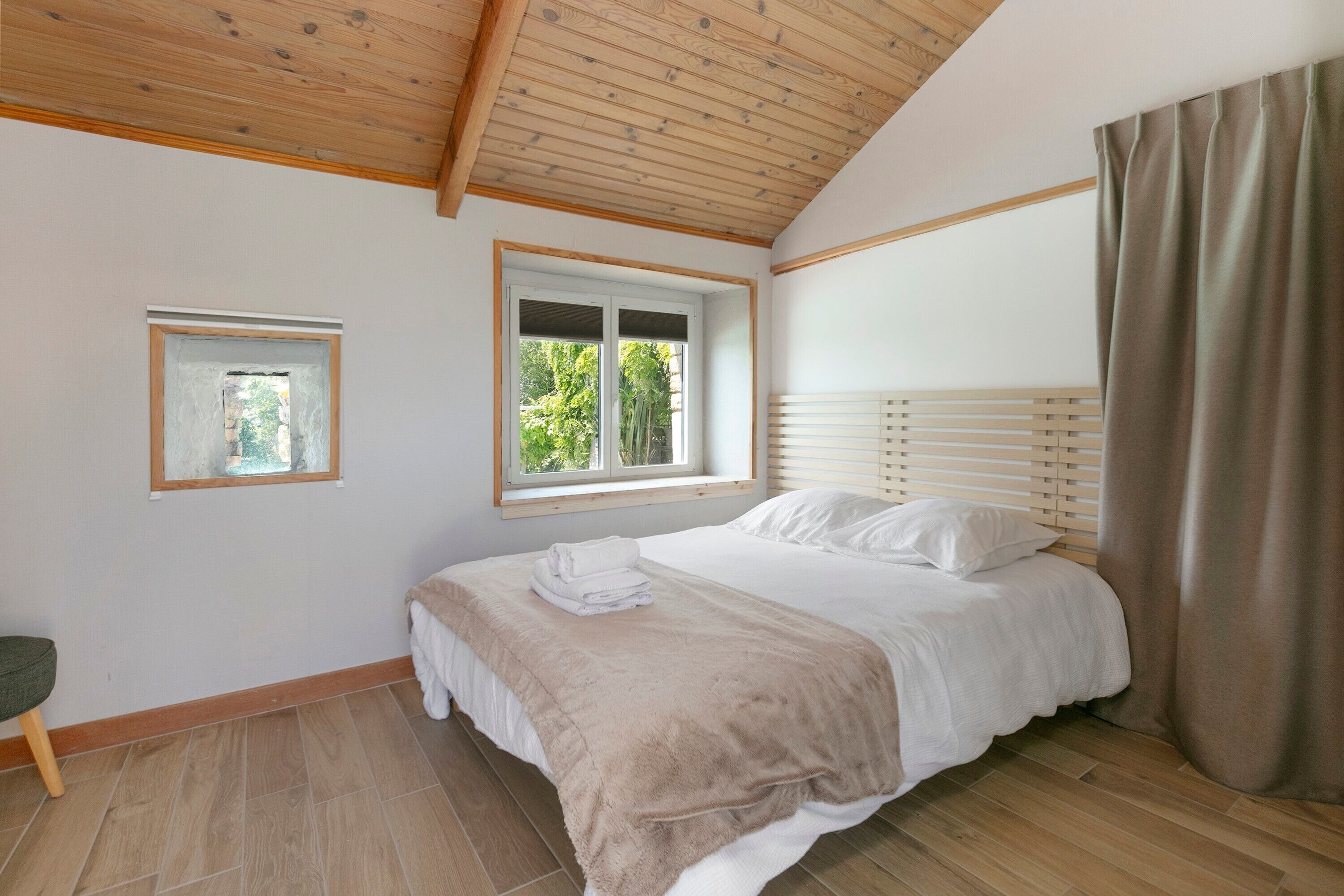 A bedroom with a bed, a window, a mirror, and a curtain.