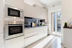 A modern kitchen with built-in appliances, a large window, and a view of the city. - Abbrescia 10 – Central Bari Apartment with Balcony, Self Check-in, Wi-Fi, Sleeps 6 (Bari)