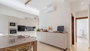 Una cucina moderna con tavolo, sedie, microonde, forno e televisione.