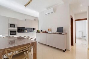 A modern kitchen with a dining table, chairs, a microwave, oven, and a TV. - Abbrescia 10 – Central Bari Apartment with Balcony, Self Check-in, Wi-Fi, Sleeps 6 (Bari)
