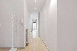 A corridor with a radiator, a white wall-mounted device, and a door at the end. - Abbrescia 10 – Central Bari Apartment with Balcony, Self Check-in, Wi-Fi, Sleeps 6 (Bari)