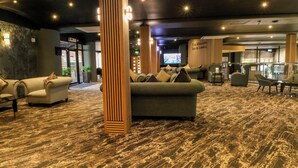 A lobby with sofas, a wooden pillar, and a bar area. - Stag Lodge (Chorley)