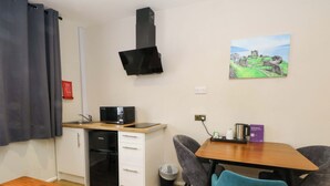 A compact kitchenette with a microwave, oven, and sink, a dining table with chairs, and a painting on the wall. - Stag Lodge (Chorley)