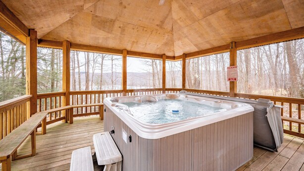 Eine Holzterrasse mit Whirlpool, Bänken und Deckenventilator.