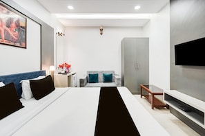 A modern hotel room with a large bed, a sofa, a TV, and a wardrobe.