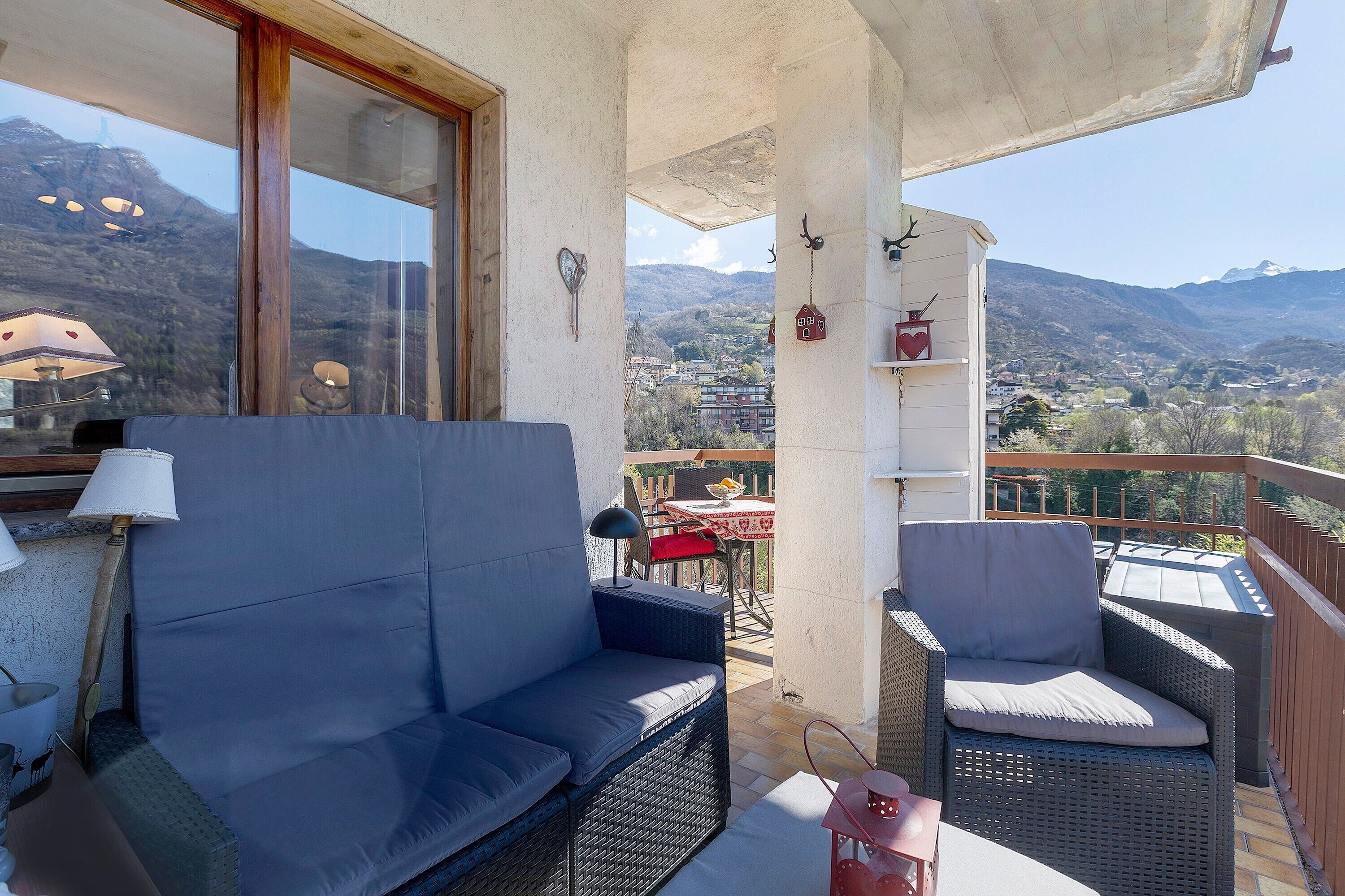 A balcony with wicker furniture, a table, and a view of a mountainous landscape.
