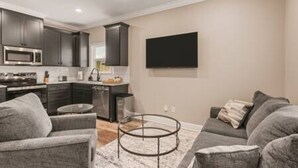 A modern kitchen with dark cabinets, a microwave, and a dining area with a round table. - Ruston Haven | Sports Complex + Dining + LA Tech (Ruston)
