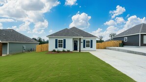 A residential property with a well-maintained lawn, a single-story house with a front porch, and a neighboring house. - Ruston Haven | Sports Complex + Dining + LA Tech (Ruston)