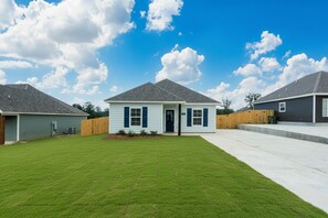 A residential property with a well-maintained lawn, a single-story house with a front porch, and a neighboring house. - Ruston Haven | Sports Complex + Dining + LA Tech (Ruston)