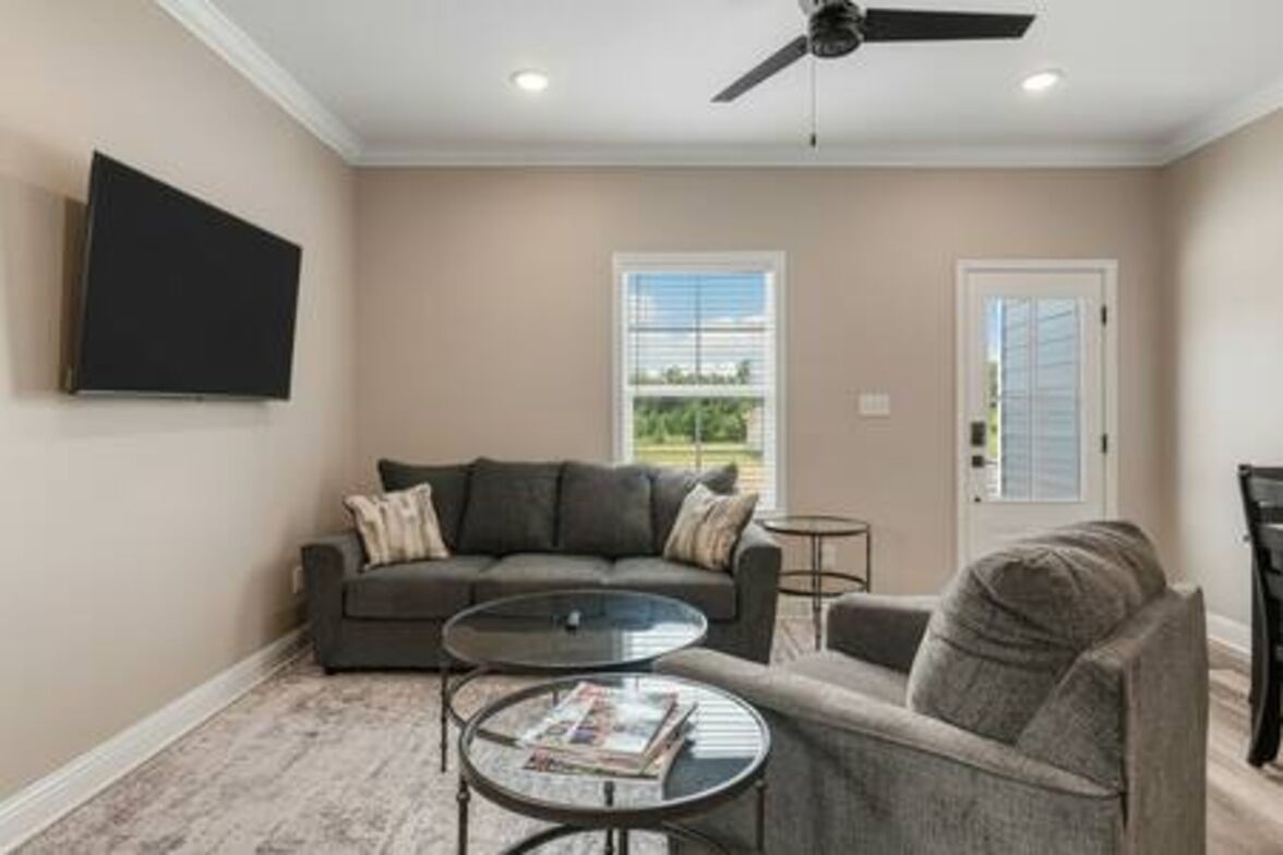 A living room with a sofa, two side tables, a ceiling fan, and a door with a window.