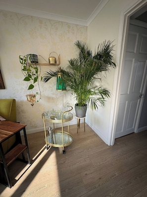 Una habitación con piso de madera, una mesa de comedor, una planta en maceta, una bandeja decorativa de metal y una puerta.