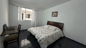 A bedroom with a bed, a desk, and a chair.